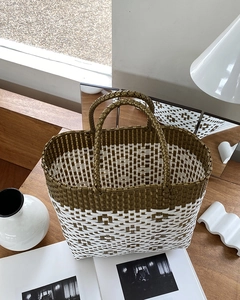 Detail of olive green and white geometric woven tote bag with round handles on wood