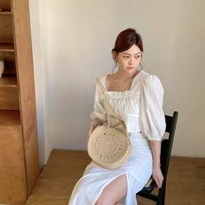 Détail du sac rond en paille beige avec texture tressée pour les vacances d'été