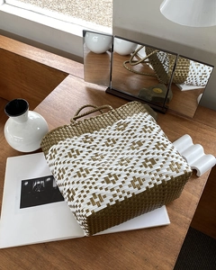Detail of handwoven brown and white geometric pattern on a large straw beach tote bag