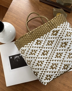 Detail of woven beach tote with geometric pattern and sturdy handles on wooden background