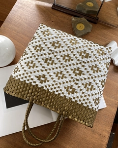 Detailed view of handmade woven tote bag with metallic bronze texture on wooden table