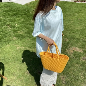 Close-up of bright yellow hand-woven beach bag with thick straps and textured pattern