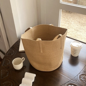 Handcrafted straw bucket bag with large capacity on a rustic wooden table