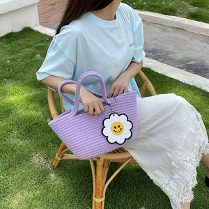 Detail of purple woven cotton rope handbag with a sunflower smiley face charm