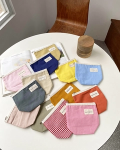 Detailed view of colorful canvas cosmetic bags with minimalist tags on a white table