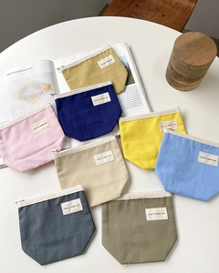Detailed view of colorful canvas makeup pouches with zippers and text labels on a desk
