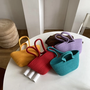 Close-up of four colored woven cotton hand bags showing thick texture and minimalist design