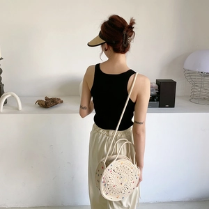 Détail d'un sac en paille beige avec broderie à pois colorés et une longue bandoulière fine