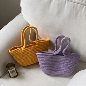 Handwoven cotton rope tote bags in yellow and lilac purple on a cozy sofa