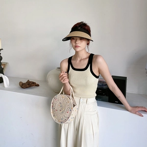 Détail d'un sac à main rond en paille tissée avec une tenue de vacances d'été minimaliste
