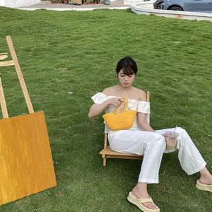 Detail of yellow handmade woven tote bag with circular handles on a wooden garden chair