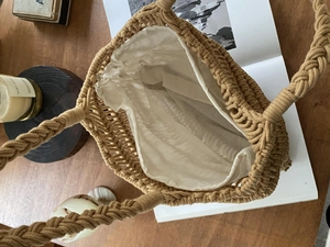 Detail of hand-woven straw tote bag with chunky braided handles and cotton drawstring liner