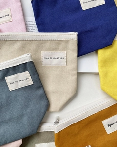 Detailed view of colorful canvas pouches with metal zippers and decorative labels