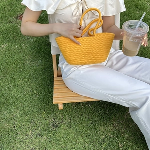 Close-up of bright yellow woven cotton rope handbag featuring textured spiral patterns