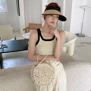 Détail d'un sac à main rond en paille avec pois colorés et chapeau de soleil tressé
