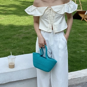Handmade sky blue woven handbag paired with white off-shoulder top and wide-leg trousers