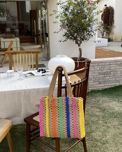 Detail of colorful striped straw tote bag showing hand-woven texture and long handles
