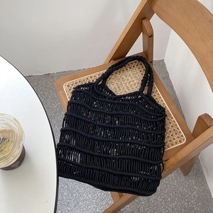 Close-up of black woven cotton tote bag texture on a designer rattan chair