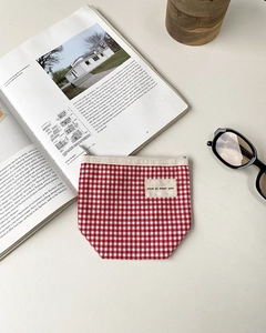 Close-up of red and white checkered canvas pouch with nice to meet you label and zipper