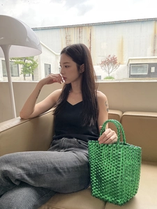 Metallic green woven basket bag featuring stylish double handles in a modern tote style
