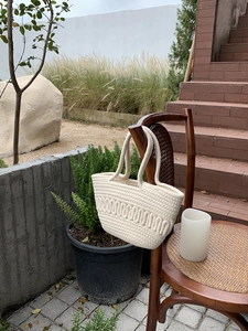 Detailed texture of cream woven cotton tote bag with unique wavy patterns on a chair