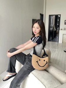 Detailed hand-woven texture of khaki shoulder bag with black smiley face design