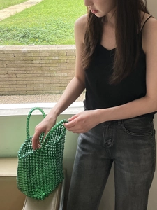 Close-up of vibrant green woven basket bag with hollow-out knit design for summer style