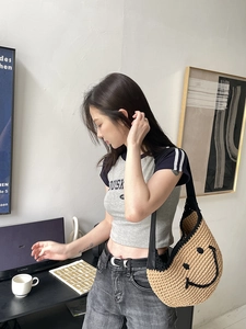 Detailed view of handmade woven shoulder bag featuring a black smile embroidery