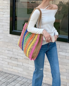 Close-up of handmade rainbow striped straw tote bag with hollow crochet weave detail