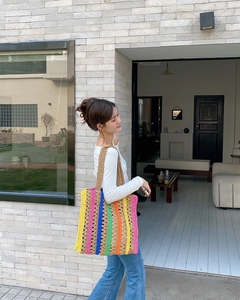 Detail of colorful handmade crochet tote bag with vibrant vertical stripes shown on shoulder