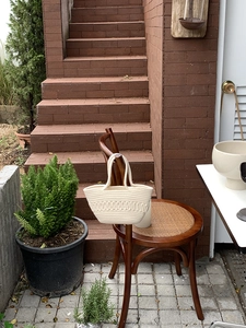 Detail of hand-woven off-white cotton rope bag hanging on a vintage wooden chair