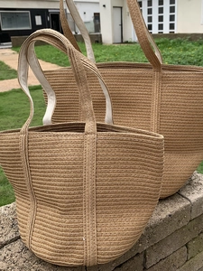 Detailed view of woven straw tote bags with textured patterns and white inner handles