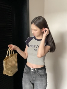 Close-up of golden metallic woven handbag paired with casual outfit and leather belt