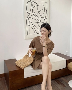 Detail of hand-woven beige wave straw bag paired with a brown knit V-neck mini dress