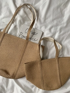 Detailed view of woven straw tote bags in two sizes with vertical textured patterns