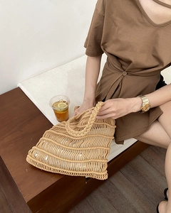 Detail of hand-woven straw tote bag with hollow wave pattern for summer beach vacations
