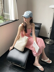 Lifestyle shot of large beige woven shoulder bag and denim bow cap on a female model