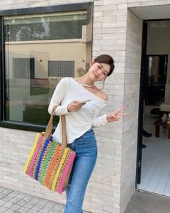 Outdoor model carrying a large rainbow striped crochet tote bag with woven handles
