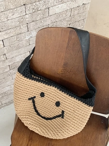 Handmade crochet shoulder bag with a smiley face design and black leather strap