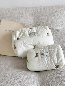 Close-up of brown bear embroidery on fluffy white quilted storage bags set of two
