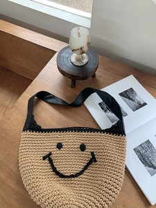 Detail of hand-woven beige cotton shoulder bag featuring black crochet smiley face pattern