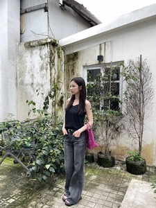 Outdoor shot of a black V-neck tank top paired with high-waisted washed denim jeans