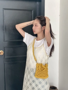 Detail of a bright yellow hand-woven crochet crossbody bag with a hollow geometric mesh pattern