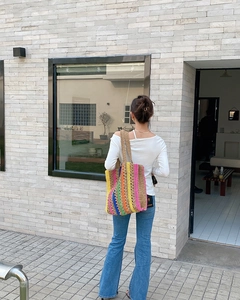Outdoor shot of a colorful crochet tote bag with rainbow stripes and woven shoulder straps