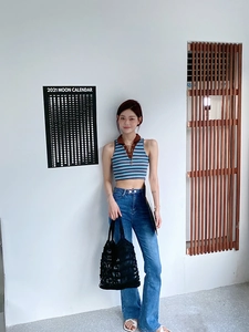 Close-up of the black woven net tote bag held by a model wearing a striped knit top