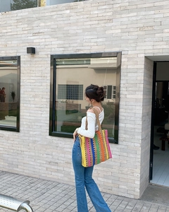 Close-up of a colorful handmade striped straw tote bag with vertical bohemian patterns