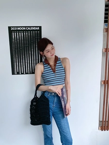 Detail of hand-woven hollow straw tote bag paired with vintage knit polo and blue denim jeans