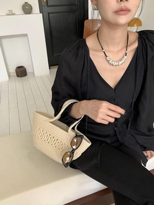 Detail of woven cotton rope handbag with hollow design paired with black fashion accessories
