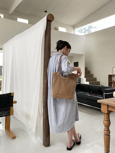 Detail of hollow hand-woven straw tote bag with thin brown leather shoulder straps