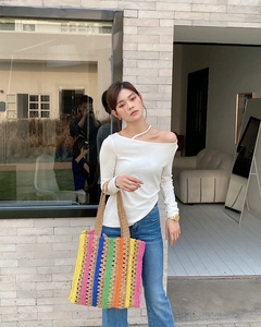 Detail of colorful striped crochet tote bag with woven texture and brown shoulder strap